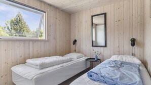 Quarto com duas camas, uma janela e um espelho.