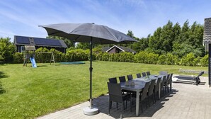 Um pátio com mesa e cadeiras, balanço e escorrega em um quintal.