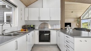 Een moderne keuken met witte kasten, roestvrijstalen apparatuur en een groot eiland.
