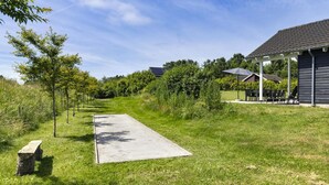 Um caminho leva a um edifício com área de estar externa e uma pérgula.
