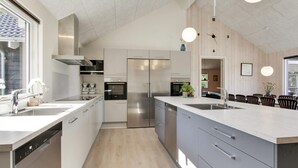 Ett modernt kök med en stor köksö, rostfria vitvaror och en matplats med stolar.