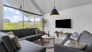A modern living room with a grey sofa set, a round coffee table, and a mounted TV. - VillaVilla 491 - Mommark, Sydjylland (Sydals)