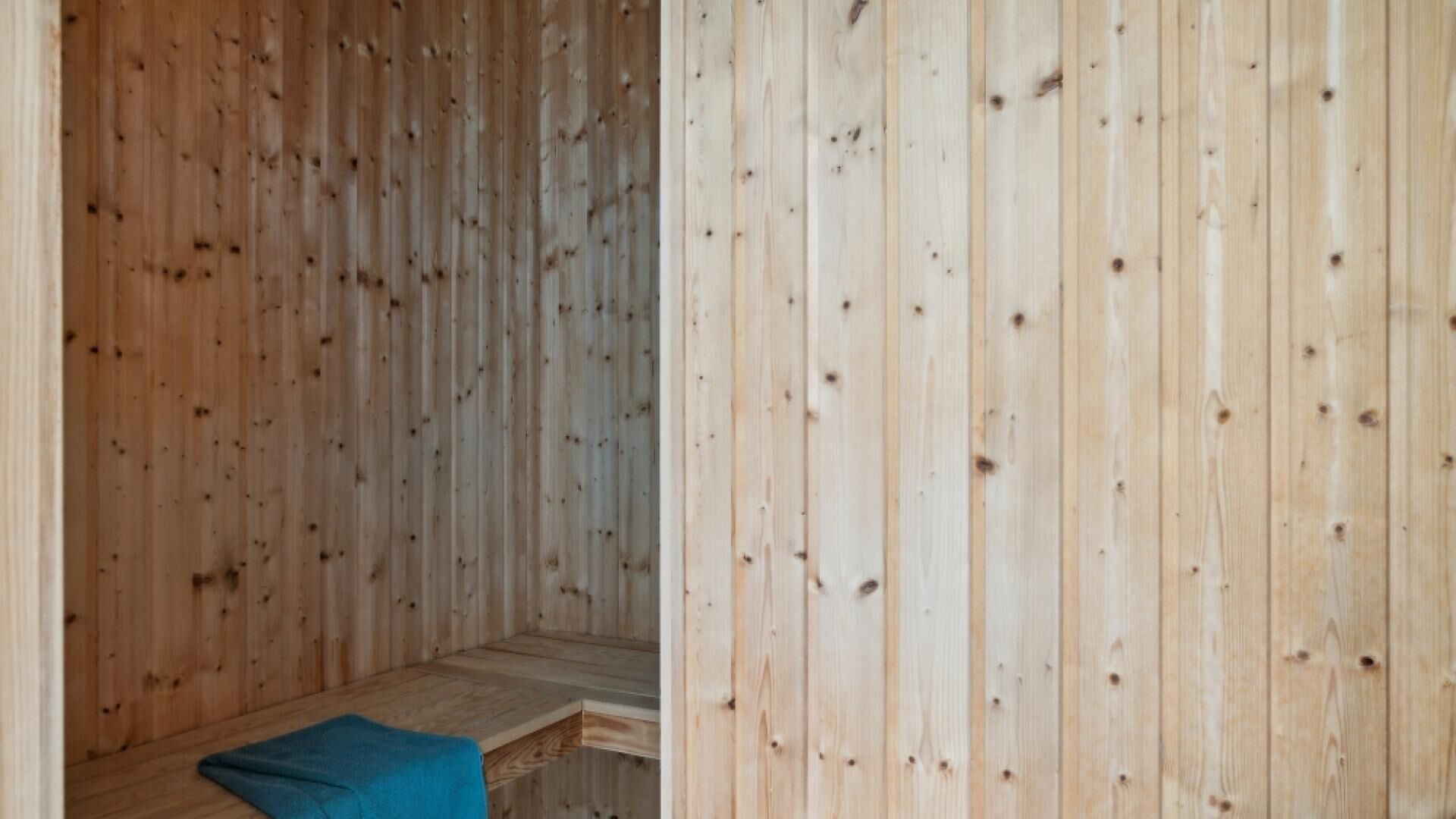 Un sauna en bois, doté d’un banc et d’un revêtement pour le banc.