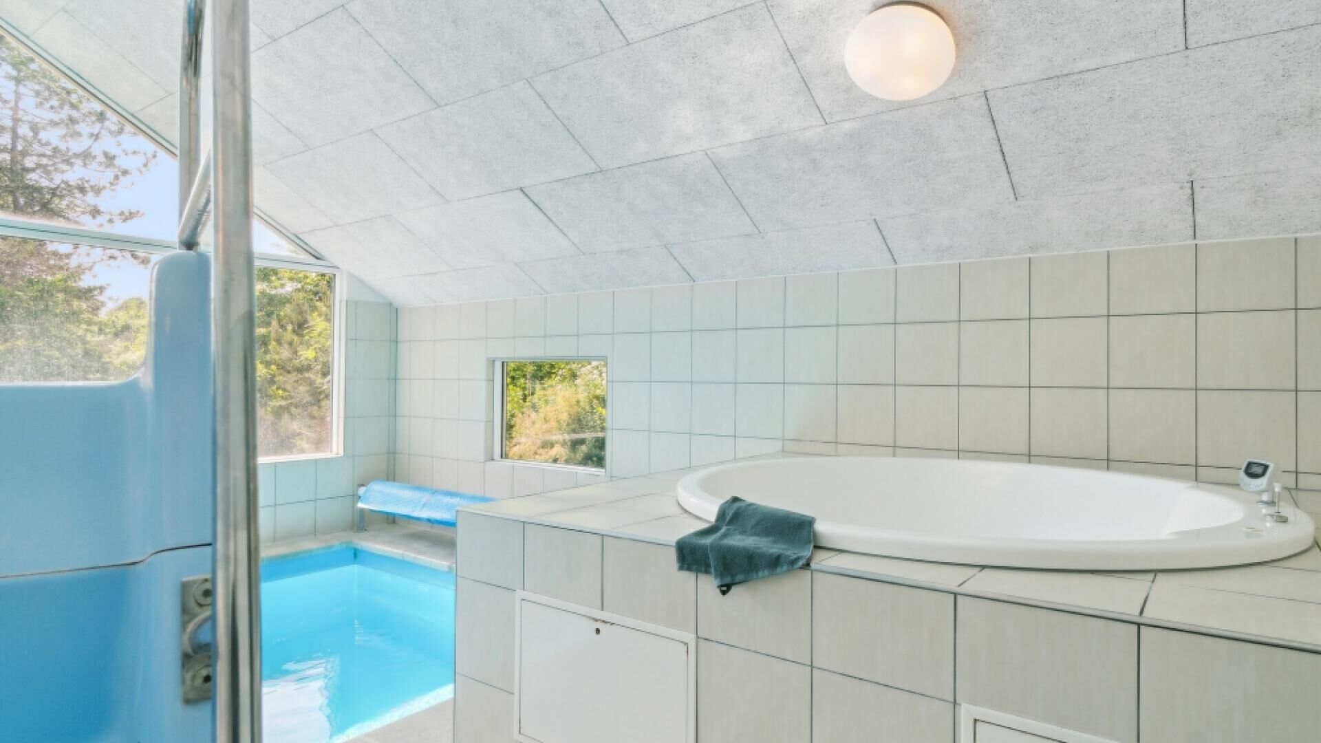 Une salle de bain moderne dotée d’une grande baignoire, d’un espace douche et d’une fenêtre offrant une vue sur la verdure.