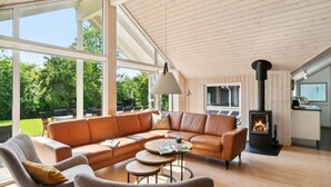 Un salón espacioso con un sofá modular grande, una chimenea y vistas al exterior.