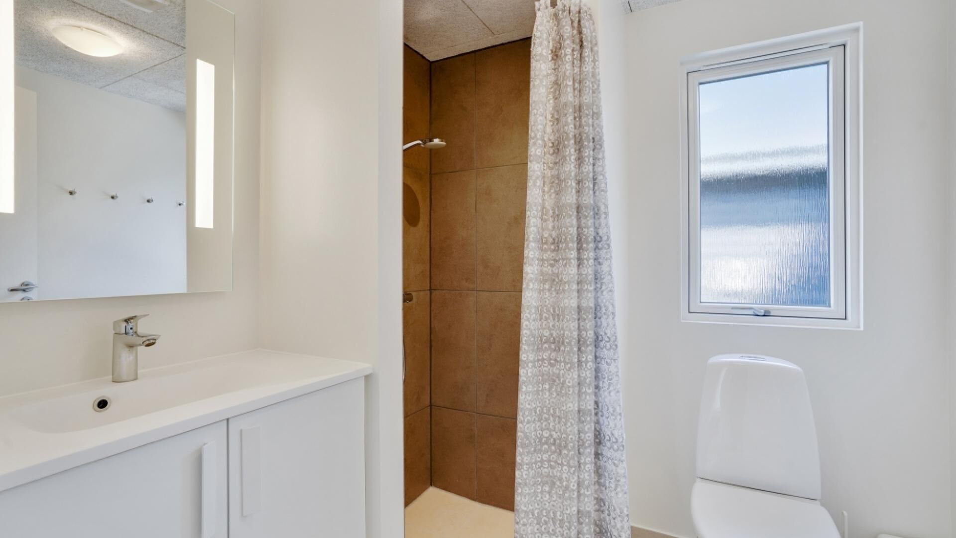 A bathroom with a shower, a toilet, a sink, and a window with a view.