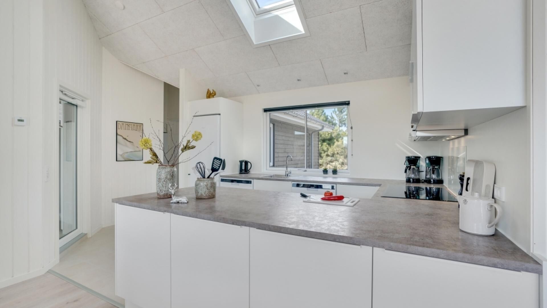 A modern kitchen with white cabinetry, a large island, and a skylight.