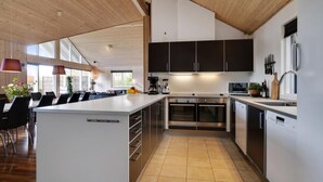 A modern kitchen with a central island, stainless steel appliances, and black cabinets.