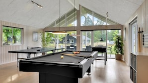 Een pooltafel in een moderne ruimte met grote ramen en natuurlijk licht.