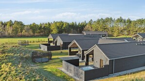 A modern, eco-friendly resort with multiple cabins featuring sloped roofs and large windows, set in a lush, green landscape with a clear sky. - VillaVilla 597 - Rømø, Sydjylland (Rømø)