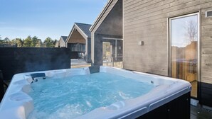 A hot tub in an outdoor setting with a wooden deck and a house in the background. - VillaVilla 597 - Rømø, Sydjylland (Rømø)