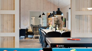 Un comedor moderno con mesa de billar, paneles de madera e iluminación colgante.