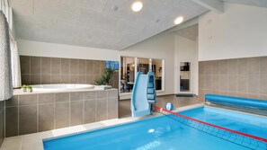 Ein Pool mit Rutsche, ein Whirlpool und Blick in einen Essbereich.
