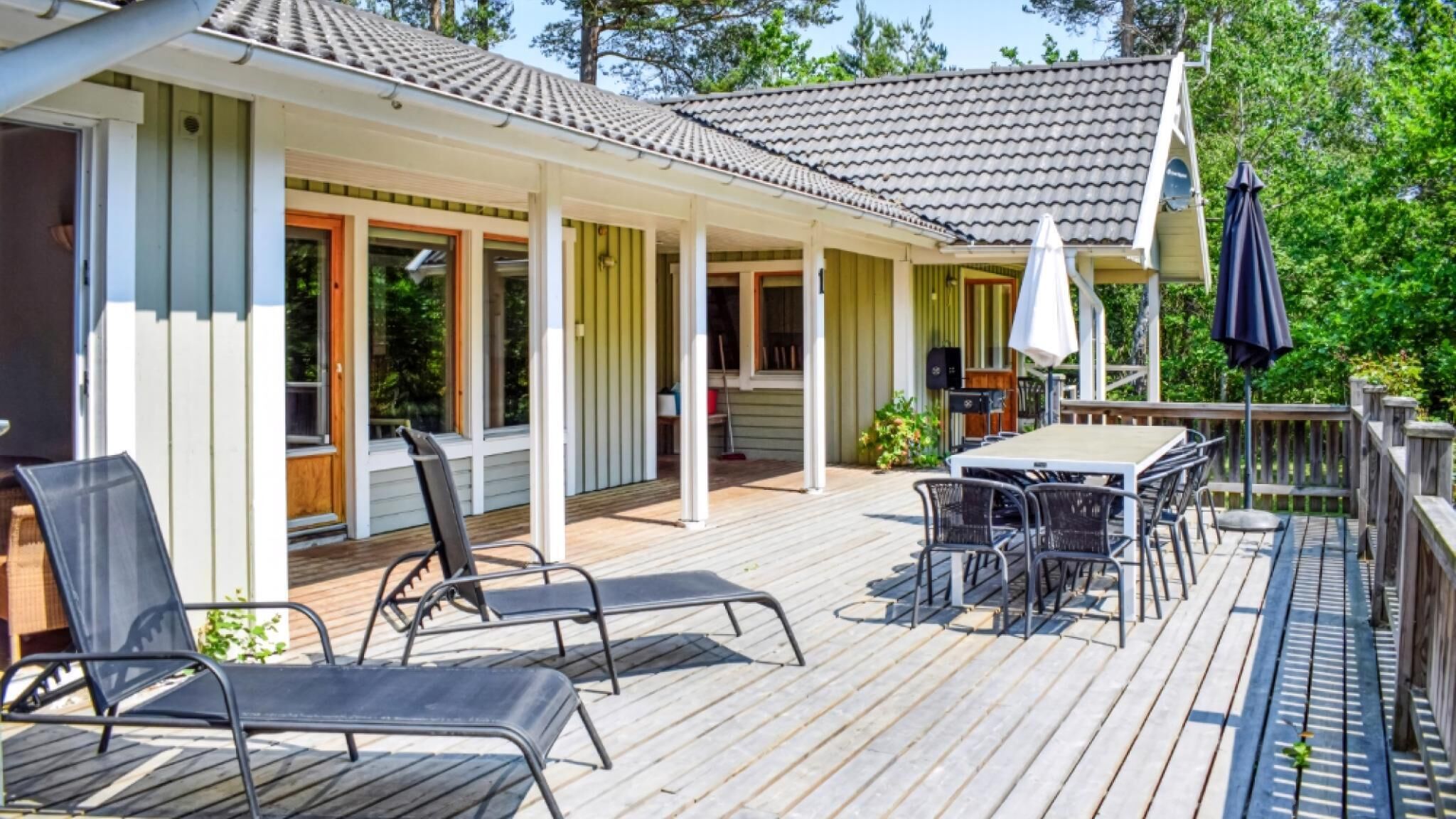 Une terrasse extérieure couverte, équipée d’une table et de chaises, d’un haut-parleur et d’un barbecue.
