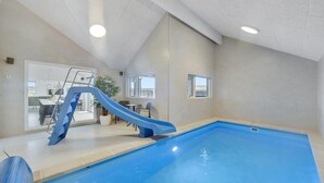 An indoor swimming pool with a blue slide, a staircase, and a potted plant. - VillaVilla 558 - Bjerregård, Vestjylland (Hvide Sande)