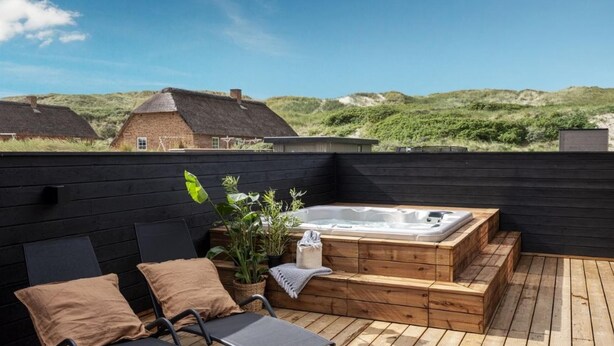 A wooden deck with a hot tub, seating area, and a view of the surrounding landscape. - VillaVilla 558 - Bjerregård, Vestjylland (Hvide Sande)