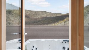 Ein Whirlpool mit einer Holzterrasse und Blick auf eine hügelige Landschaft.