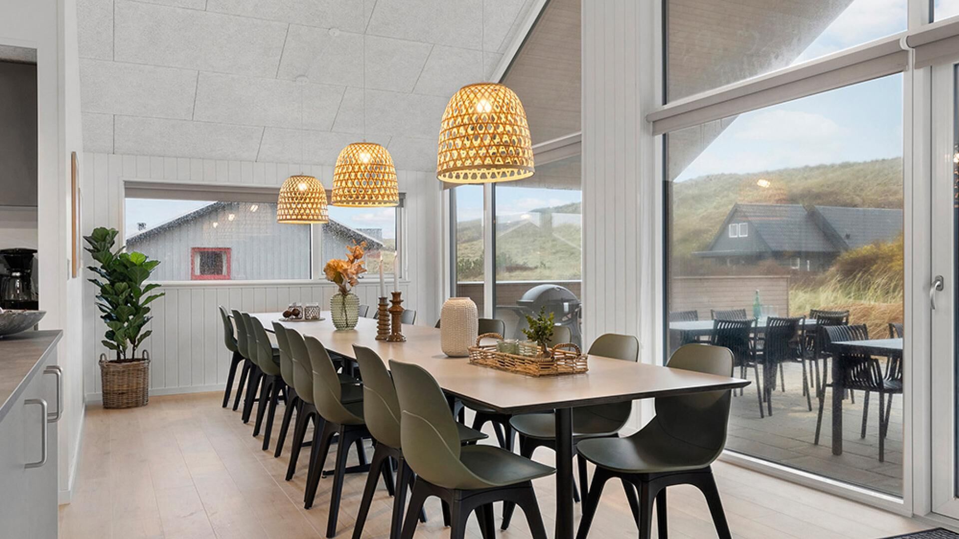 A spacious dining area with a long table, modern chairs, and pendant lights.