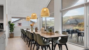 Ein geräumiger Essbereich mit einem langen Tisch, modernen Stühlen und Pendelleuchten.