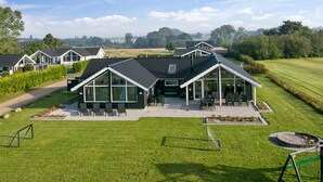 Een modern huis met een ruim terras, een zwembad en een verzorgd gazon.