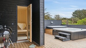 Ett utomhusområde med en uppvärmd pool, en trädäck, en bastu och grillutrustning.