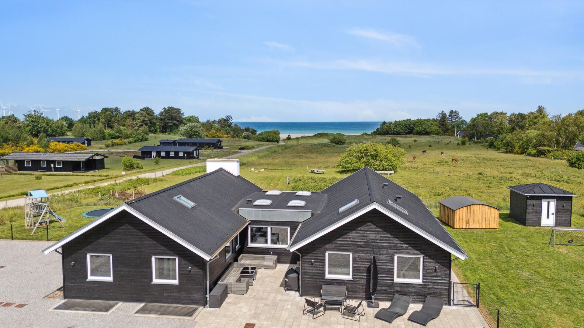 Une maison moderne dotée d’une grande terrasse, d’une piscine et offrant une vue sur la mer.