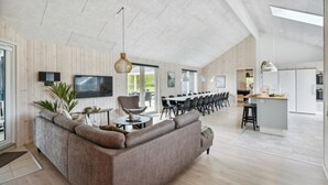 En moderne stue med sofa, TV og spiseplads.