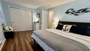 A bedroom with a large bed, wooden flooring, and light blue walls.
