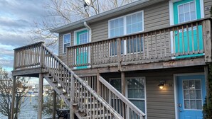 A two-story house with a wooden deck and a blue door.