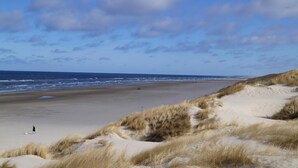 En strand med sandklitter og havet i baggrunden.