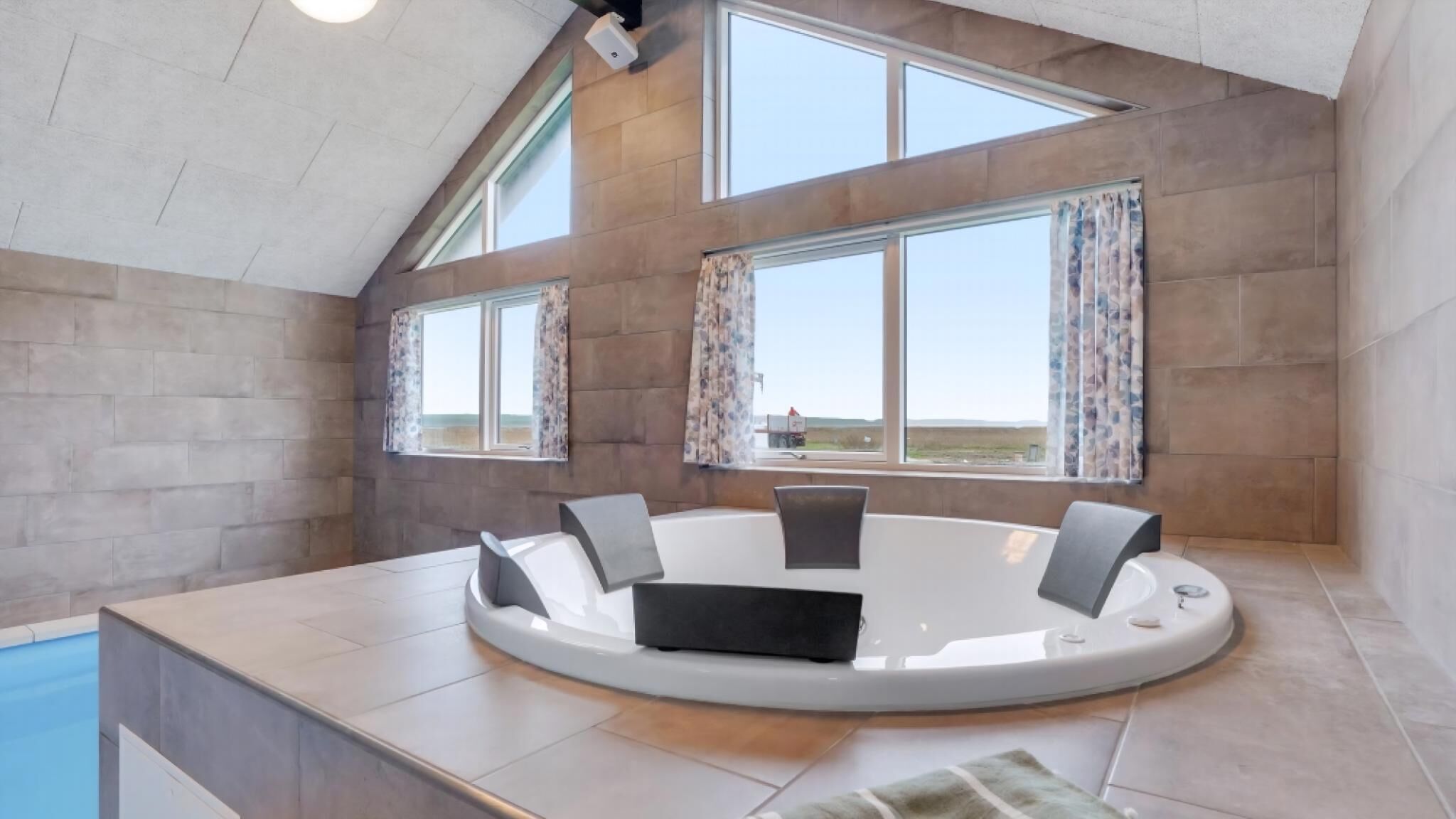 A modern interior with a circular seating area, large windows, and a view of the landscape.