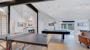 Ein moderner Indoor-Erholungsbereich mit Tischtennisplatte, Billardtisch und Kicker.