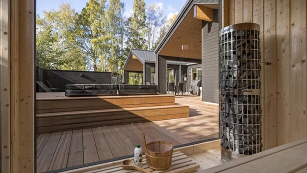 A wooden deck with outdoor seating, a stone water feature, and a view of a forested area. - VillaVilla 638 - Gilleleje, Nordsjælland (Gilleleje)
