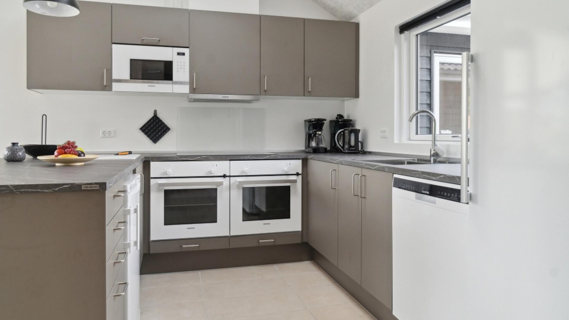 A modern kitchen with two ovens, a microwave, and a dishwasher.