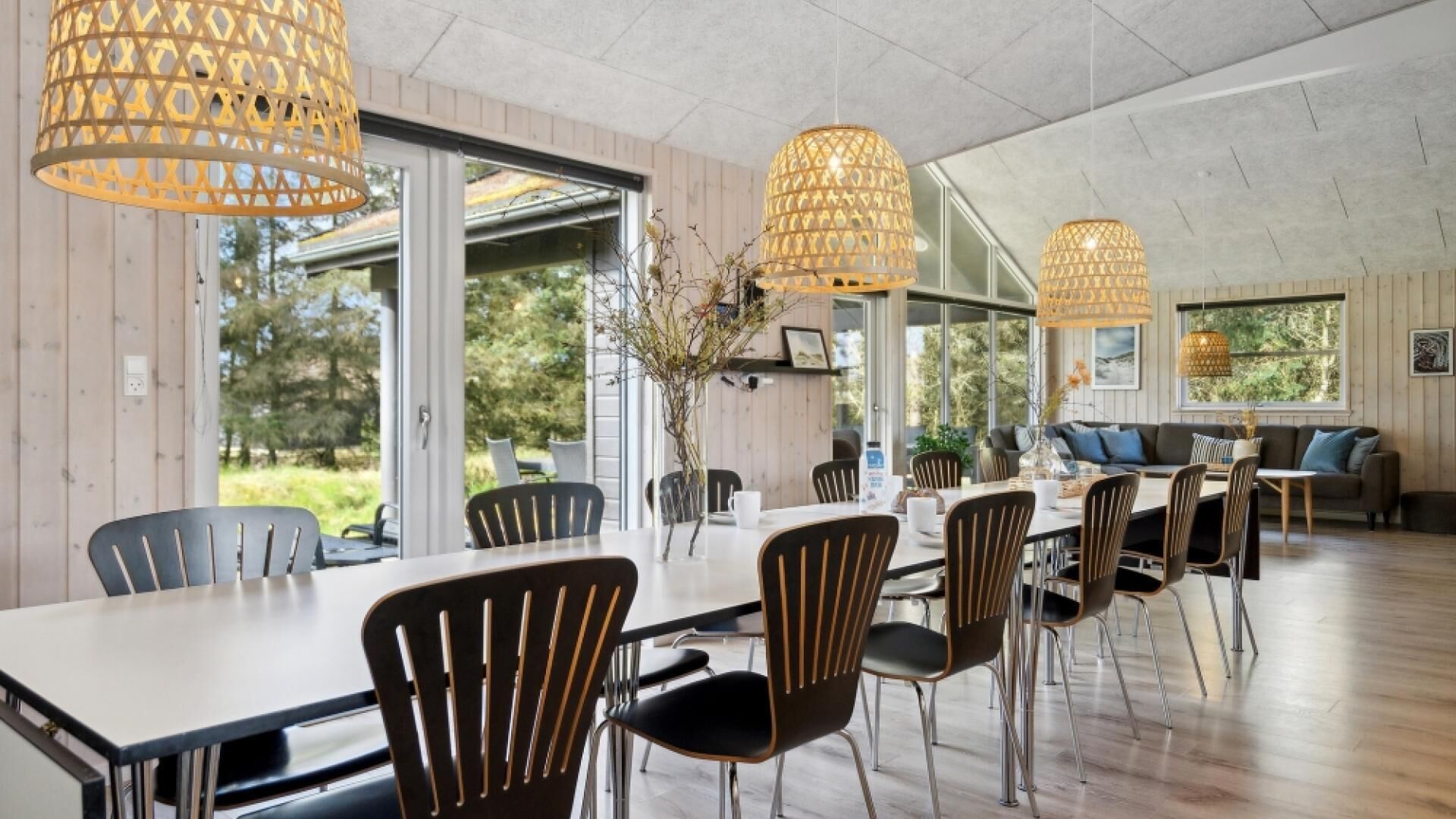 Un'ampia sala da pranzo con un lungo tavolo, numerose sedie e lampadari a sospensione.