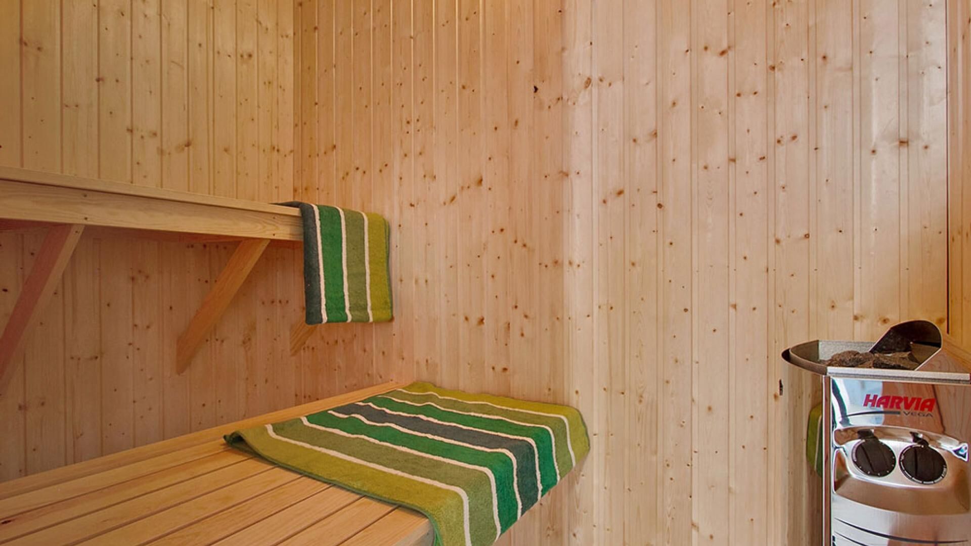 Ein Saunaraum mit Holzwänden, einer Bank und einer Harvia Saunaanlage.