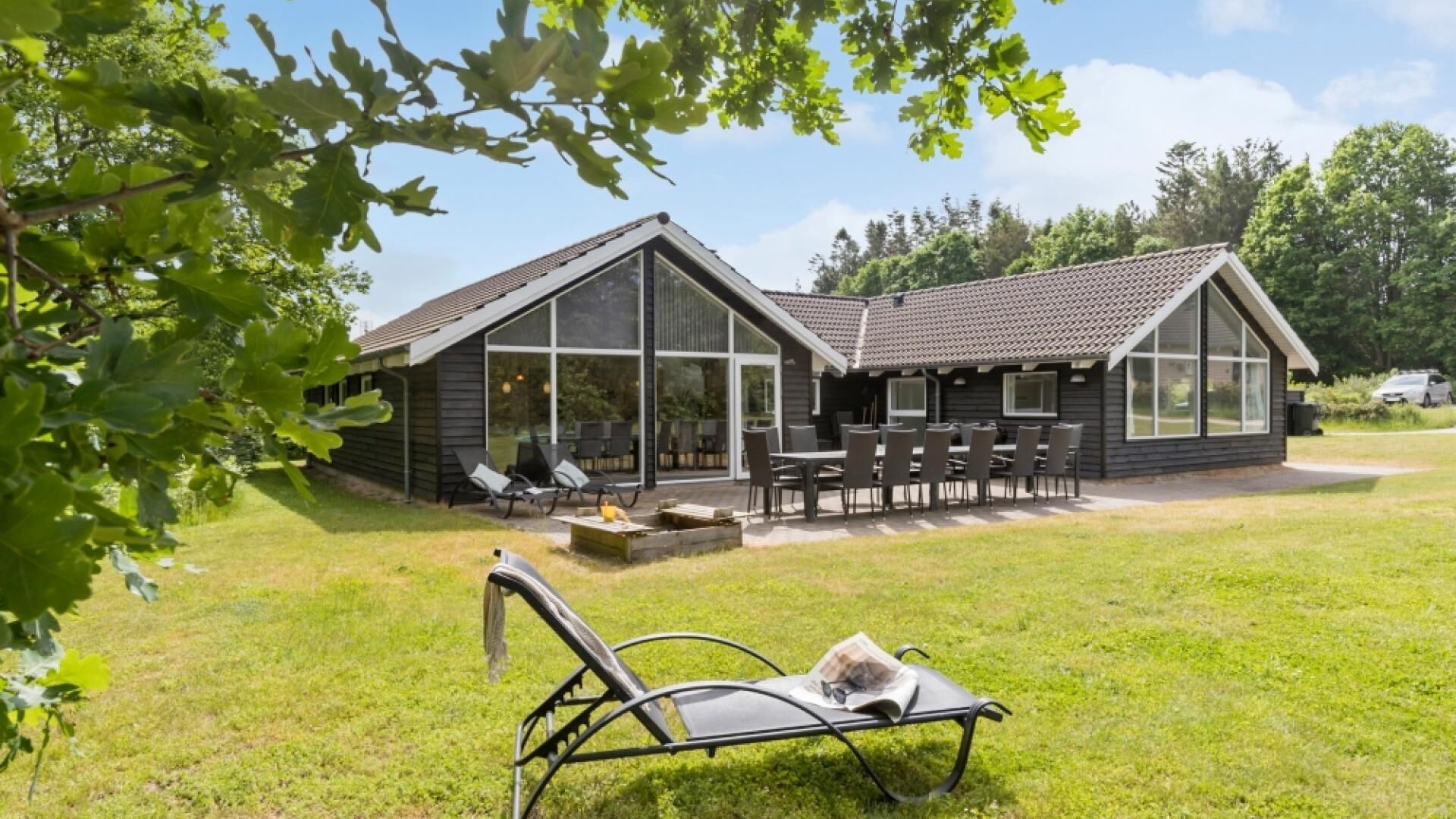 Ein modernes Haus mit Terrasse, großen Fenstern und Gartenmöbeln.