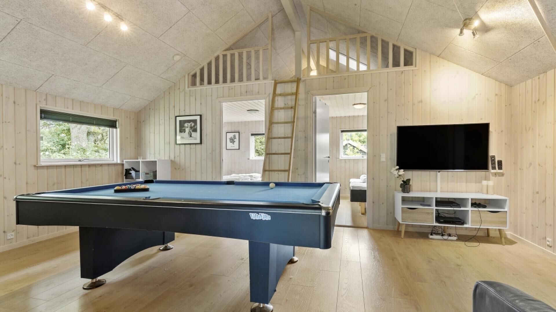 A pool table in a room with wooden walls and a sloped ceiling.