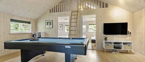 A pool table in a room with wooden walls and a sloped ceiling.