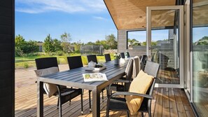 Eine Terrass mit Esstisch, Stühlen und einer Glastür, die auf einen Balkon führt.