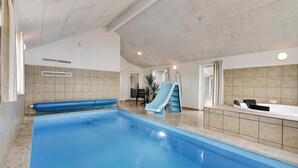 Piscina interna com escorrega, hidromassagem e porta que dá para outro cômodo.