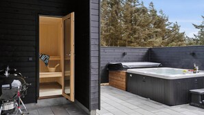 Una cabaña de madera con sauna, jacuzzi y zona de barbacoa.