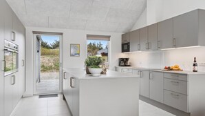 Una cocina moderna con armarios blancos, una isla grande y vistas al exterior.