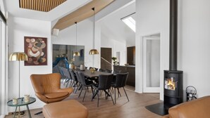 A spacious living area with a dining table, leather chairs, a fireplace, and a modern kitchen in the background. - VillaVilla 584 - Hornbæk, Nordsjælland (Dronningmølle)