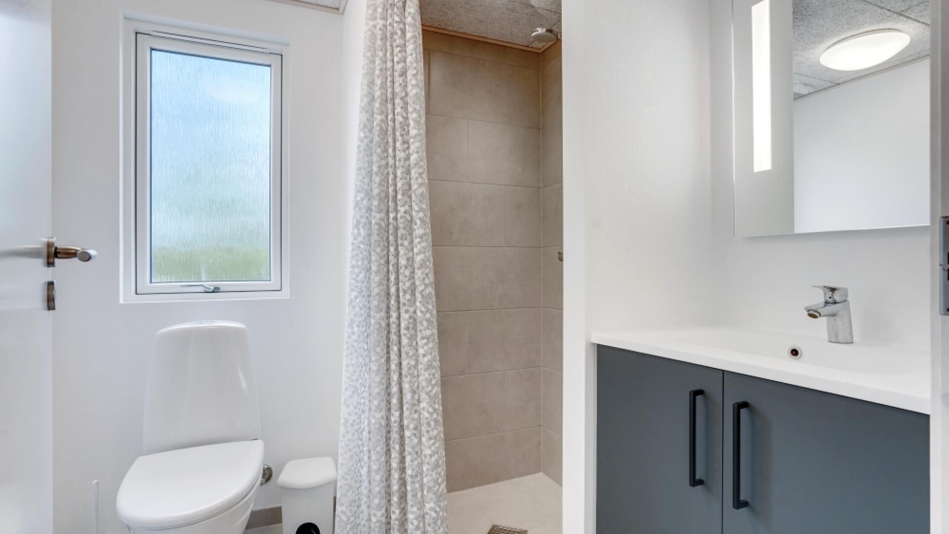 Une salle de bain moderne équipée de toilettes, d’une douche et d’un meuble-lavabo.