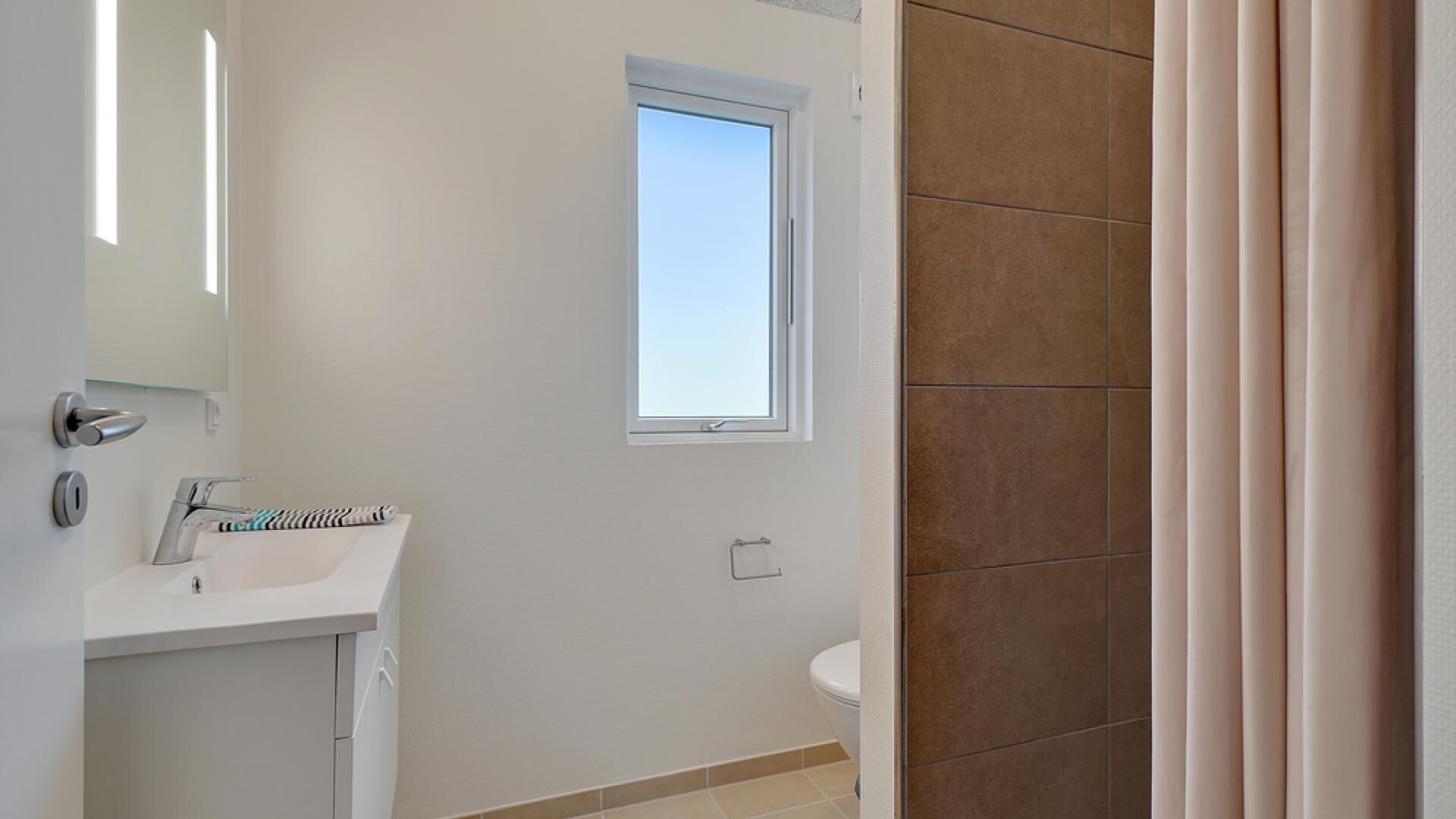 A bathroom with a window, a sink, and a toilet.