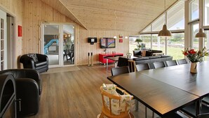 Ein geräumiger Wohnbereich mit Holzboden, einem großen Esstisch, einer Couch und einem Fernseher.