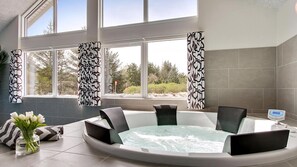 A modern bathroom with a large bathtub, two black chairs, a digital thermometer, and a vase of white flowers. - VillaVilla 399 - Blåvand, Vestjylland (Blåvand)