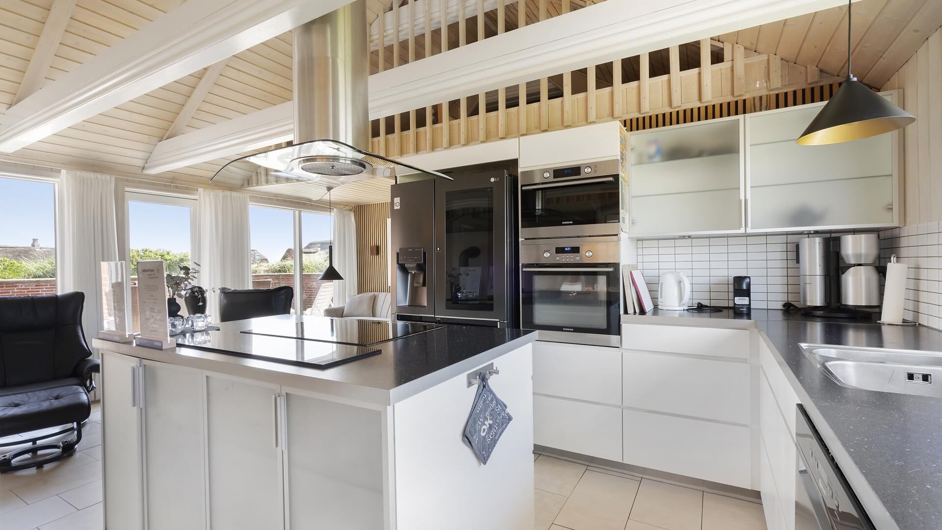 A modern kitchen with a central island, built-in appliances, and a view of the outdoors.