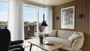 Ein modernes Wohnzimmer mit einer Couch, einem Sessel, einem Tisch und einer Pendelleuchte.